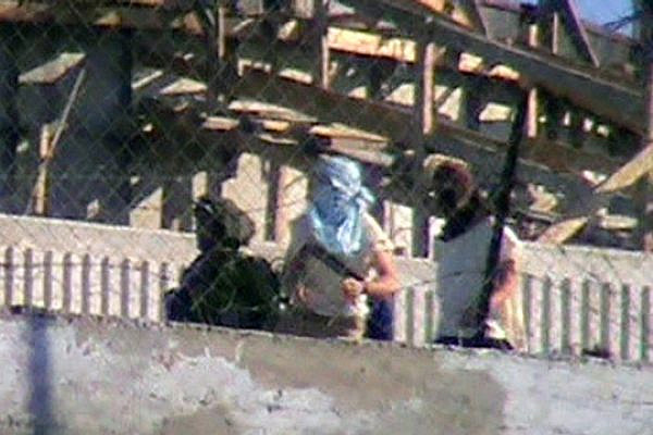 IDF soldier escorting masked settlers as they attack the Palestinian village of Urif, January 6, 2014. (Screenshot of video by Osama Safdi/B'Tselem)