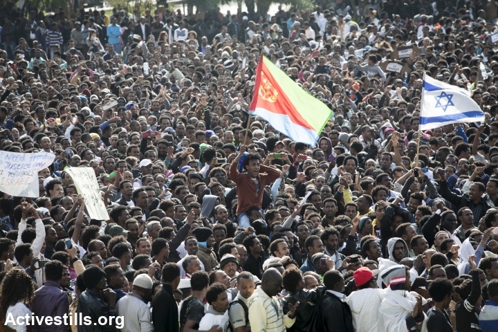 A man holds an Eritrean flag as asylum seekers protest continued detentions and demand Israel examine their asylum claims, January 5, 2014. (Photo: Activestills.org)