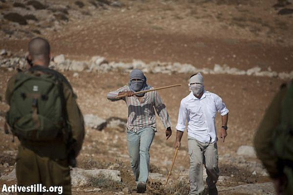 File photo of settlers threatening Israeli activists and Palestinians with sticks in front of the Ma´on settlement, South Hebron hills. (Photo by: Oren Ziv/Activestills.org)