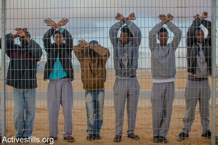 African asylum seekers jailed in Holot detention center protest behind the prison's fence, as other asylum seekers take part in a protest outside the facility, in Israel's southern Negev desert, February 17, 2014. 