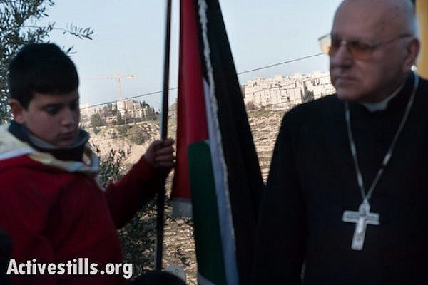 With the Israeli settlement Gilo visible on a nearby hillside, Palestinians hold a prayer service as a nonviolent witness against the Israeli separation barrier in the West Bank town of Beit Jala, February 8, 2013.  (Photo by Ryan Rodrick Beiler/Activestills.org)