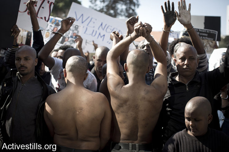 Victims of torture camps in the Sinai Desert, Egypt, show their injuries as African asylum seekers shout slogans during a protest in front of Israel Ministry of Interior offices in Tel Aviv, February 11, 2014. African asylum seekers marched from Levinsky park to protest against the new Holot detention center for African immigrants and called on the Israeli government to recognize their refugee rights. (photo: Activestills.org)