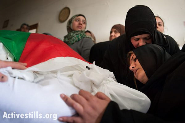 Iman Katamish (right) mourns among family members at the flag-draped body of her mother Noha, Aida Refugee Camp, West Bank, April 15, 2014. Noha Katamish, who had asthma, died from the effects of a tear gas grenade fired into her home by Israeli forces the previous day. She was the mother of one daughter.