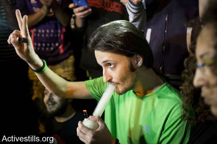 An Israeli man smokes a bong as over 1500 protesters blocked a road leading to the Israeli parliament, during a demo calling to the Israeli government to legalize the use of cannabis, West Jerusalem, April 20, 2014 (Activestills.org)