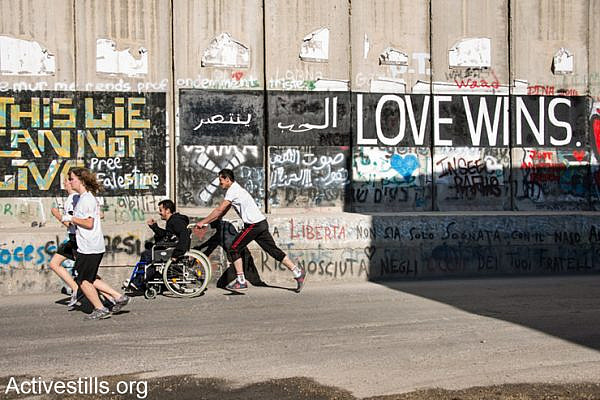 A Palestinian runner pushes a friend in a wheelchair along the Israeli separation wall dividing the West Bank town of Bethlehem during the second annual Palestine Marathon, April 11, 2014. Some 2,500 Palestinian and 700 international runners participated in 5K, 10K, half marathon and full marathon races under the title “Right to Movement”. Full marathon runners had to complete two laps of the same route, as organizers were unable to find a single course of 42 uninterrupted kilometers under Palestinian Authority control.