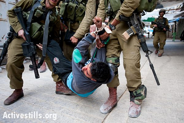 Israeli soldiers arrest a Palestinian youth, who shows signs of being beaten, following a demonstration in the West Bank city of Hebron, March 1, 2013. (photo: Activestills.org)