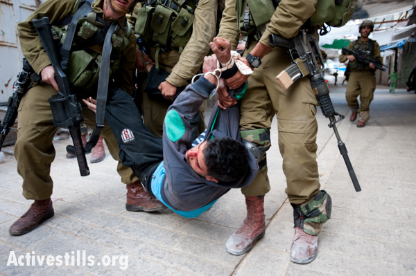 Israeli soldiers arrest a Palestinian youth, who shows signs of being beaten, following a demonstration against the occupation and in support of Palestinian prisoners the West Bank city of Hebron, March 1, 2013. (photo: Ryan Rodrick Beiler/Activestills.org)