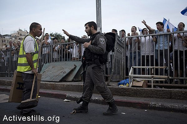 A Palestinian cleaning worker argues with Israeli settlers as during a protest against the 'flag march', in which Israeli settlers and Ultra-nationalists march through Damascus Gate in East Jerusalem, on May 28, 2014, celebrating the anniversary of its capture in the 1967 Six-Day War.
Police prevented from Palestinians to gather and  protest against the march, and attacked journalists that were covering  the event. (Oren Ziv/Activestills.org)