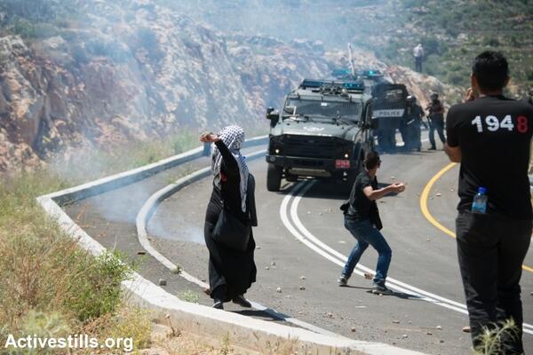 Palestinians throw stones at an Israeli military jeep during a Nakba Day protest in the village of Al-Walaja. (photo: Activestills.org)