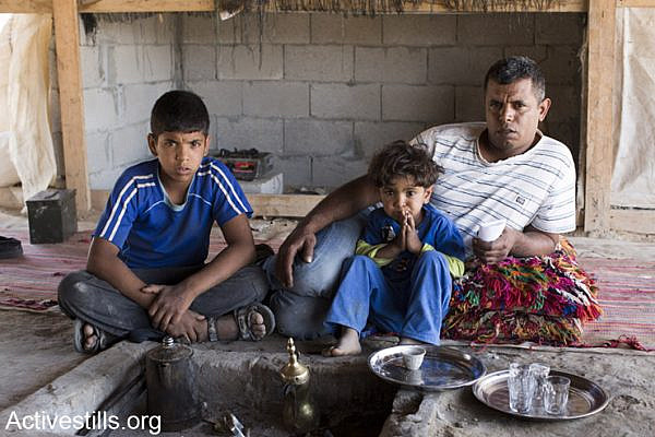 Eyad Adisan and his children sit in the family tent just hours after police and inspectors paid his home a visit.