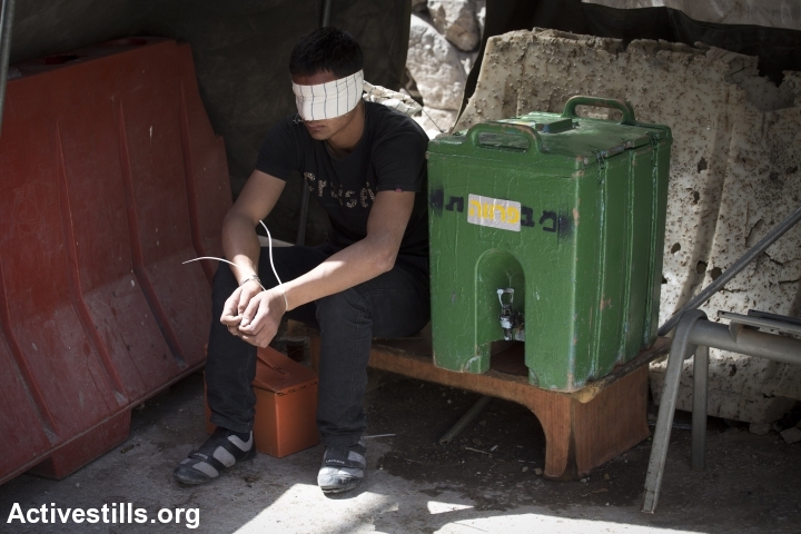 A Palestinian youth, arrested and blindfolded by Israeli soldiers during the closure on Hebron. (photo: Activestills)