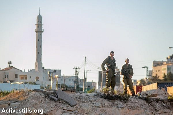 Israeli soldiers stationed at the entrance to the West Bank city of Hebron, seen on June 15, 2014. A complete closure was put on the city after three Israeli teenagers went missing near a West Bank settlement. The three, all students at a Jewish seminary, went missing late on June 12 as they were hitchhiking between Bethlehem and Hebron and are believed to have been kidnapped. (Photo by Yotam Ronen/Activestills.org)