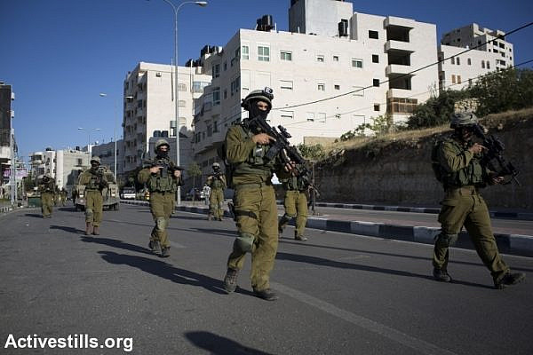 IDF soldiers walk through Hebron. (photo: Activestills)