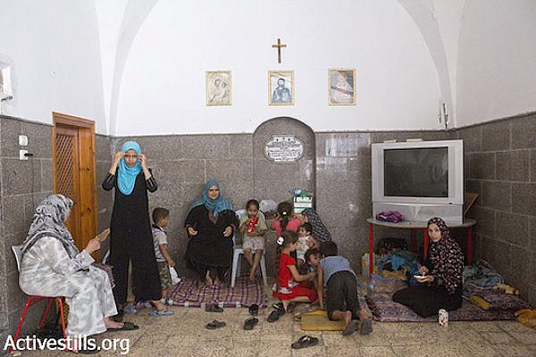 Palestinians sit inside central Gaza City's Church of St. Porphyrius where they find refuge, July 22, 2014. (Anne Paq/Activestills.org)