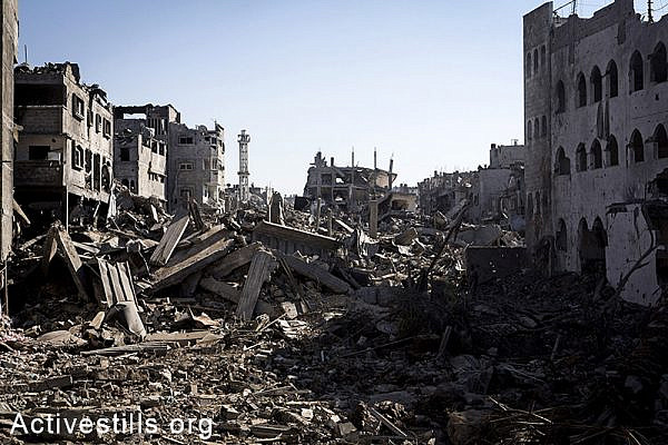 A destroyed quarter in Shujaiyeh neighborhood in the east of Gaza City, during a ceasefire, July 27, 2014. During the ceasefire on 26 July, many Palestinians went back to Shujaiyeh to inspect the damages together with medics who attempted to rescue injured or collect bodies. Dozens of bodies were collected but many remain as Palestinians do not have all the necessary equipment to dig. Israeli attacks turned the neighborhood into a scene of utter devastation, with entire buildings flattened and thousands forced to flee.  Israeli attacks have killed more than 1,000 Palestinians and injured around 5,000 in the current offensive. (Anne Paq/Activestills.org)