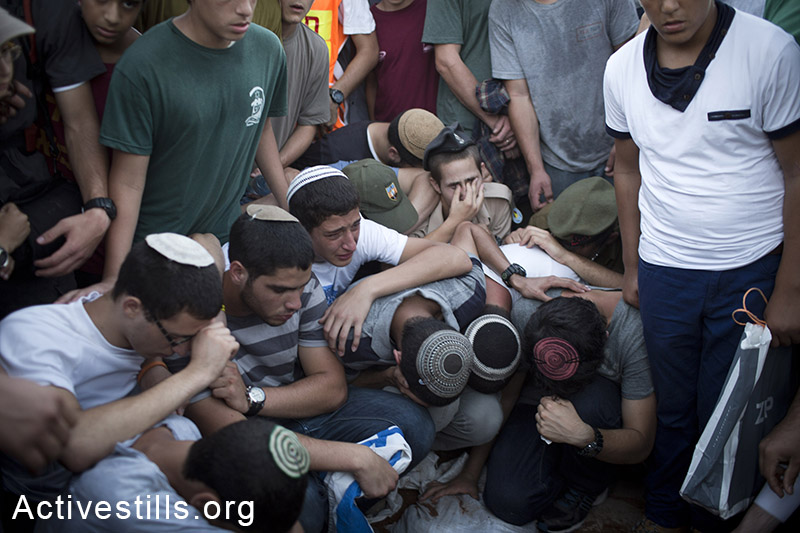 Family and friends of Eyal Yifrah, Gilad Shaar, and Naftali Fraenkel, three Israeli teenagers who were abducted over two weeks ago, take part in their funeral in the city of Modiin, Israel, Tuesday, July 1, 2014.  Tens of thousands of mourners arrived ro Modiin in central Israel for a funeral service for three teenagers found dead in the West Bank after a two week searches, raids and arrests in the West Bank, as Israel accused Hamas of abducting and killing the young men. (Oren Ziv/Activestills.org)