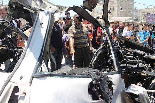 Gaza Civil Defense Directorate crews remove the wreckage of a car targeted by an Israeli airstrike in the northern Gaza Strip, July 10, 2014. The attack killed three men riding in the car who were taken to Kamal Udwan hospital. Two were identified as Mahmoud Waloud and Hazim Balousha. (Photo by Joe Catron)