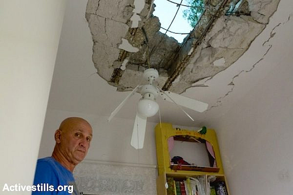 An Israeli looks at damage to his home in a kibbutz near border with the Gaza Strip on Wednesday, July 9, 2014. (Photo by Yotam Ronen/Activestills.org)