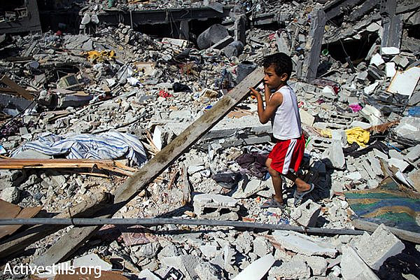 Nader Obu Odeh, 6 years old, gathers some wood from destroyed houses to help make a fire. August 12, 2014. (Basel Yazouri/Activestills.org)
