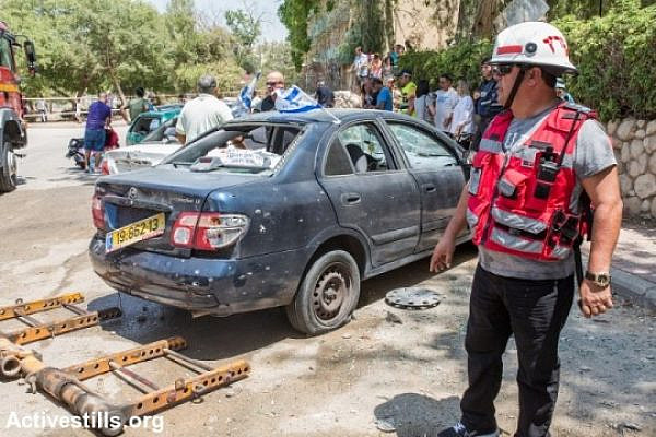 Israelis check the scene in which a rocket shot from the Gaza Strip has hit a street in the city of Beer Sheva, August 22, 2014. (photo: Activestills)