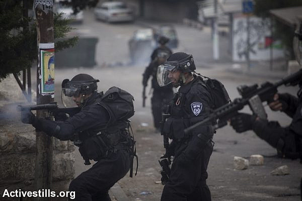 An Israeli policeman shoots tear gas during a protest following the death of a Muhammad Sunuqrut, in the neighborhood of Wadi Joz in East Jerusalem on September 8, 2014. Muhammad Sunuqrut, 16, was wounded by police gunfire in the Wadi Joz neighborhood on August 31 and died from his injuries on September 7. (photo: Activestills)
