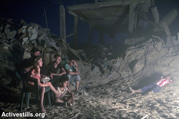 Palestinians gather around a fire in the at-Tuffah district of Gaza city, which was heavily attacked during Israel’s latest offensive, Gaza City, September 6, 2014. The family of eight returned to their home, which is in danger of collapse due to the damage. Their home, like all the buildings in the area, is neither connected to the electricity or water infrastructure. (Photo by Anne Paq/Activestills.org)