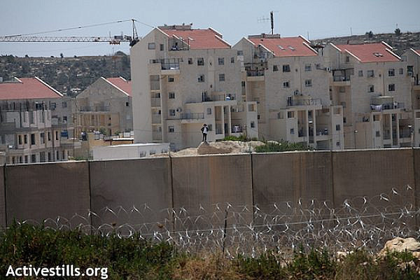Israel’s separation barrier stands on land belonging to the Palestinian village of Bil’in; the wall was built surrounding the Israeli settlement of Modi’in Illit (seen in the background). In a protracted court battle, Bil’in managed to win back some of its land but landowners are still cut off from a significant portion which has been appropriated by the Jewish settlement - both to build on and as a “security zone.” (Anne Paq/Activestills.org)
