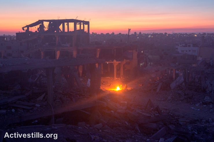 Palestians gather near a fire in the At-Tuffah district of Gaza City, which was heavily damaged by Israeli attacks during the latest offensive, Gaza City, September 6, 2014.