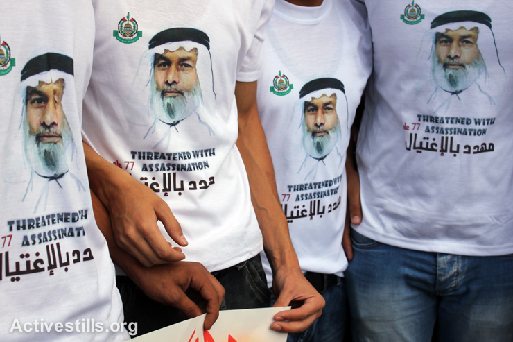 Protesters wear t-shirts with the portrait of Ahmad Haj Ali during a solidairy demonstration in front of his house in Al Ain refugee camp, Nablus, September 7, 2014. Haj Ali, 77, is a Hamas member of the Palestinian legislative council and is wanted by Israeli forces. According to his family, Israeli forces have threatened to assassinate him. Israeli authorities had issued orders to Haj Ali to turn himself as part of the massive arrest campaign launched against Hamas members this summer, but he refused to comply. Haj Ali has been imprisoned 17 times under administrative detention. Today, 34 members of the Palestinian legislative council are imprisoned in Israel, most of them are under administrative detention, meaning that they have not been charged with any crime.