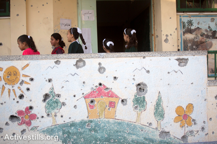 Palestinian students walk past a damaged school building wall on their second day of school, in the Sobhi Abu Karsh Basic School in Shujayea neighborood, Gaza City, September 15, 2014. The school year started with a three-week delay, due to the latest Israeli offensive. During the attacks, 29 schools were destroyed, and at least 190 suffered damage. The first weeks of the Gaza school year were dedicated to recreational activities to help children to overcome their trauma.