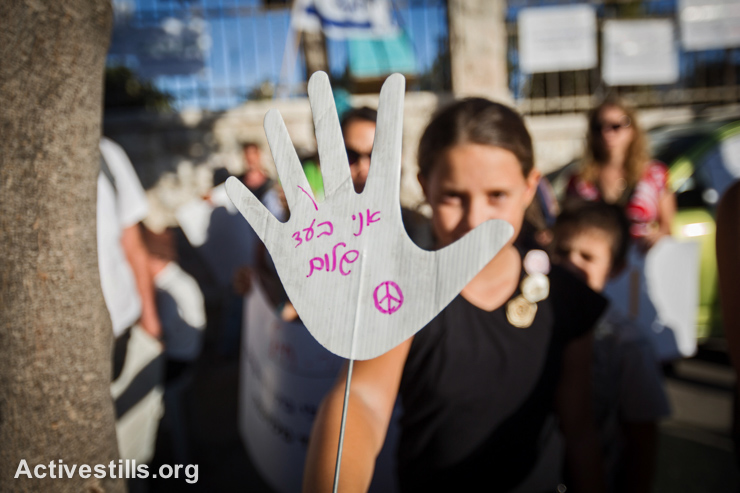 A protester holds a sign in Hebrew reading, "I am for peace," during a demonstration organized by the "Other Voice" movement from southern Israel in front of the Prime Minister's house, West Jerusalem, September 22, 2014. Protesters demanded an immediate start to political negotiations to resolve the conflict.