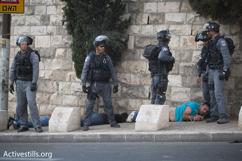 Israeli police stand over Palestinians they have arrested at a demonstration against restrictions placed on Muslim men accessing the Aqsa Mosque, October 15, 2014. (Photo by Oren Ziv/Activestills.org)