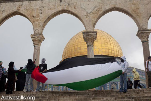 Palestinian youth hold a Palestinian flag outside the Aqsa Mosque in the Haram al-Sharif/Temple Mount compound, East Jerusalem. (Photo: Oren Ziv/Activestills.org)