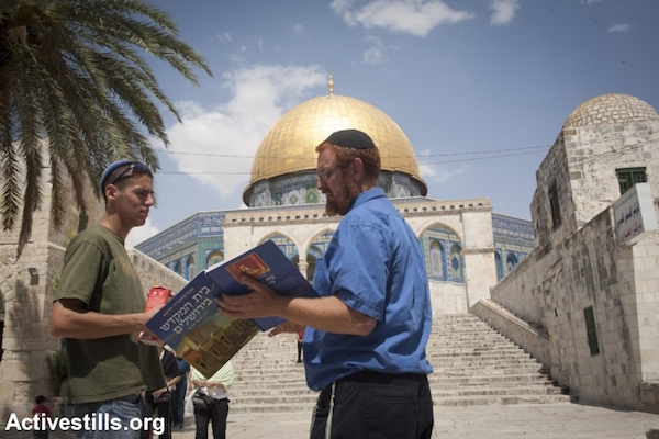Right-wing activist Yehuda Glick holding a book depicting the Jewish Temple while standing in front of the Aqsa Mosque in Jerusalem, May 21, 2009. (Photo by Oren Ziv/Activestills.org)
