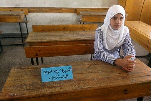 Rawan Sabah sits next to where her friend, Ra'ed Joudah, used to sit in class. Joudah was killed by an Israeli airstrike along with five of her family members. (photo: Awni Farhat)
