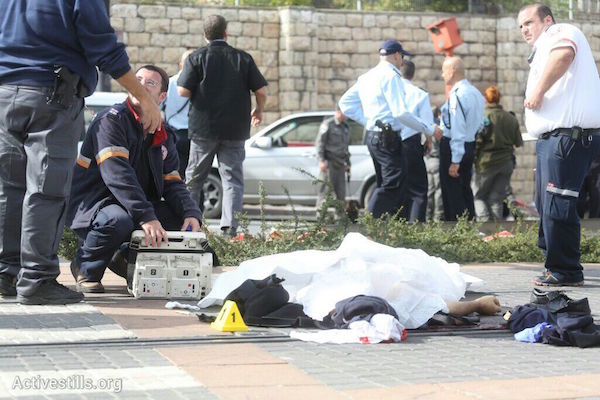 Police investigators stand around the body of a Palestinian man who ran over a group of Israeli pedestrians in Jerusalem, November 5, 2014. Police shot and killed the man shortly after the attack. (Photo by Oren Ziv/Activestills.org)