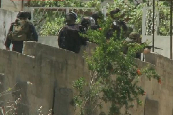 Screenshot of CNN footage showing what appears to be a Border Police officer shooting at demonstrators in Beitunia on Nakba Day, May 15, 2014. In the video, a puff of smoke and shell can be seen coming from the third-to-left officer’s weapon.