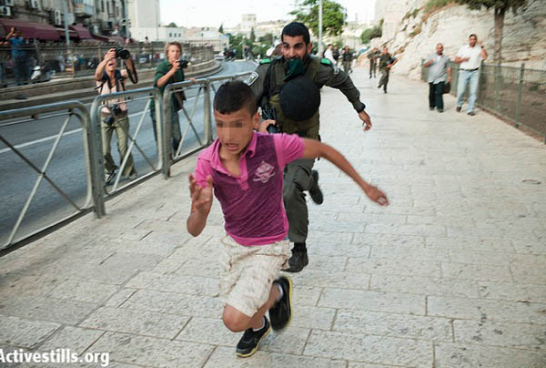 Border Police officer chasing Palestinian boy at Jerusalem Day event, 2012. (photo: Activestills)