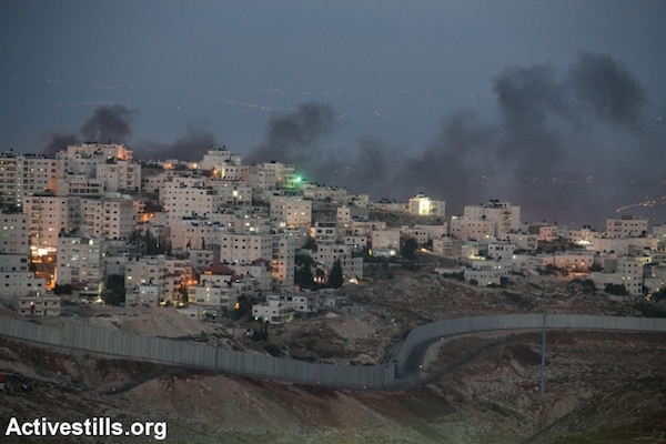 Smoke is seen rising over the East Jerusalem neighborhood of Issawiya as Palestinian youth clash with Israeli police, November 5, 2014. Earlier in the day, a Palestinian man drove into a crowd of pedestrians in Jerusalem, killing a Border Police officer and wounding over a dozen others. (Photo by Yotam Ronen/Activestills.org)