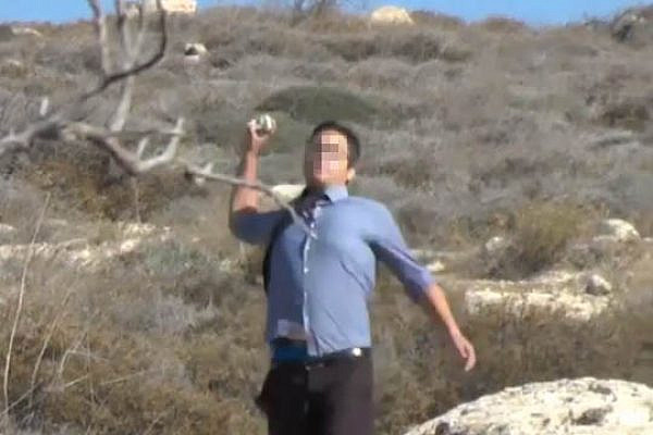 Settler from Pnei Kedem throws stones at Palestinian farmers. (YouTube screenshot)