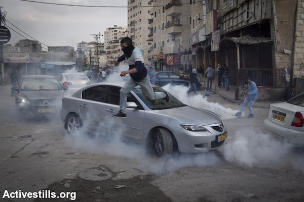 A Palestinian runs to take cover from tear gas during clashes with Israeli police in the Palestinian refugee camp of Shuafat in east Jerusalem, on November 5, 2014