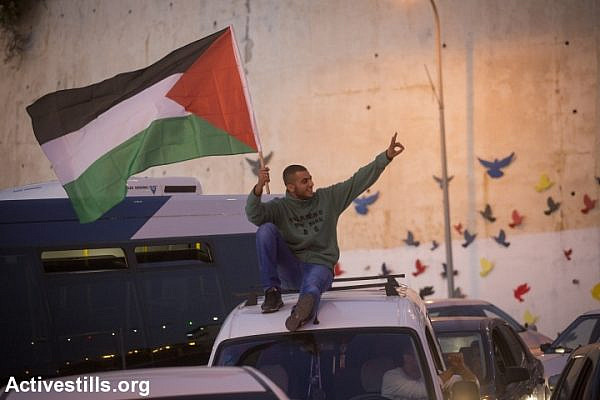 A Palestinian citizen of Israel waves a Palestinian flag during a protest against the police killing of Khir Hamdan in Umm al-Fahm. (photo: Oren Ziv/Activestills.org)