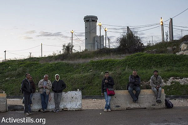 Palestinian laborers wait outside the Sha’ar Ephraim checkpoint separating the West Bank and Israel for their Israeli employers to pick them up, December 22, 2014. (Oren Ziv/Activestills.org)