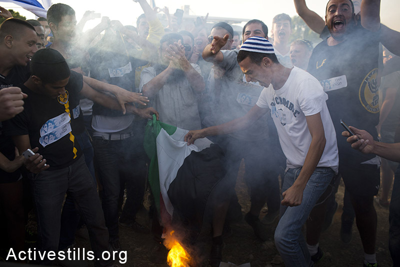 Right wing Israelis burn the Palestinian flag and shout racist slogans, during an anti-Palestinian protest at the Gush Etzion junction, next to the Palestinian town of Bethlehem, following the kidnapping of three Israeli teenagers four days ago, West Bank, June 16, 2014. By: Oren Ziv/Activestills.org