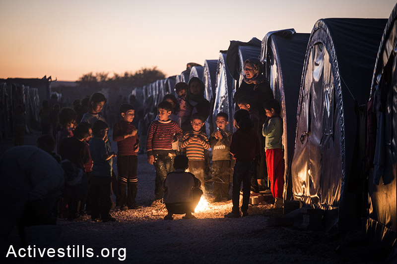 Refugee warm up near a fire at the Arin Mirkhan refugee camp, Turkish-Syrian border, October 2014. Photo: Faiz Abu-Rmeleh/Activestills.org