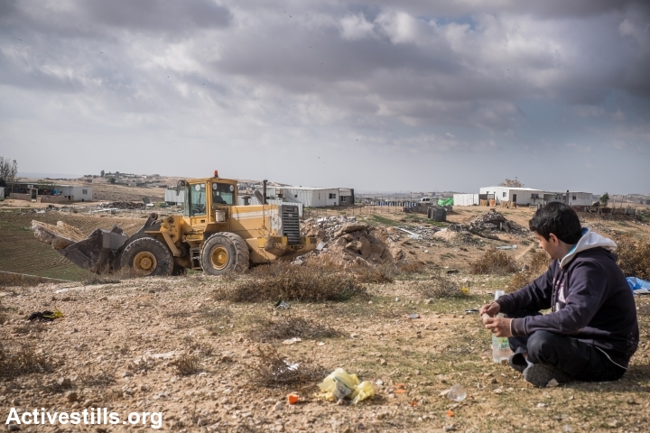 A young Bedouin watches as a bullzdozer rented by his family demolishes their own home in the recognized village Sawa, Negev Desert, December 23, 2014. (photo: Yotam Ronen/Activestills.org)