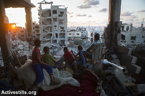 A Palestinian family sits in their destroyed home in the at-Tuffah district of Gaza City, which was heavily attacked during summer’s Israeli offensive, September 21, 2014. An estimated 18,000 housing units were destroyed or severely damaged, leaving more than 108,000 people homeless. (Photo by Anne Paq/Activestills.org)