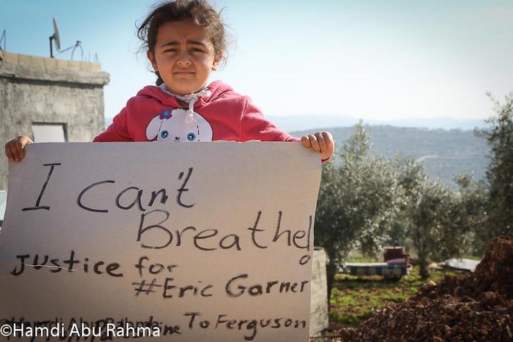A girl from the West Bank village of Bil’in carries a sign expressing solidarity with protests against the police killing of Eric Garner, December 5, 2014. (Photo by Hamdi Abu-Rahme)