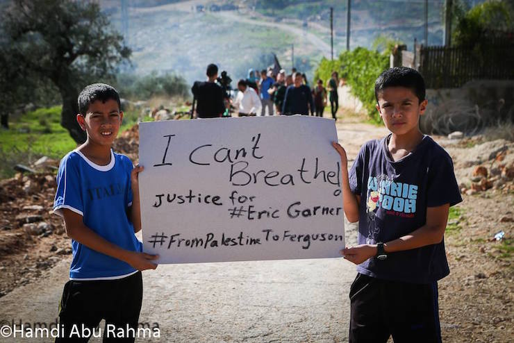 Youth from the West Bank village of Bil’in carry a sign expressing solidarity with protests against the police killing of Eric Garner, December 5, 2014. (Photo by Hamdi Abu-Rahme)