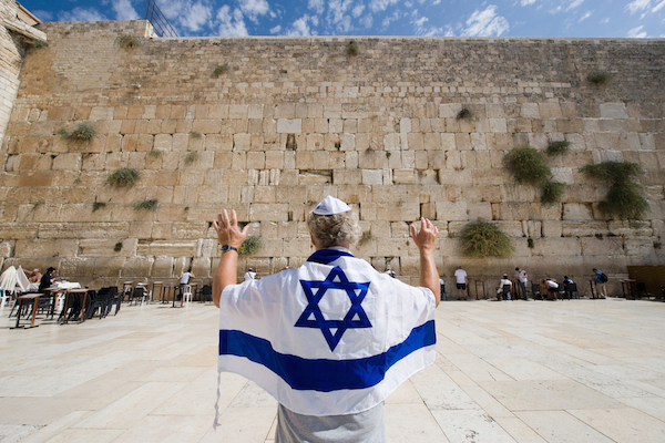 Illustrative photo of a man wearing an Israeli flag at the Western Wall. (By Shutterstock.com / Robert Hoetink)